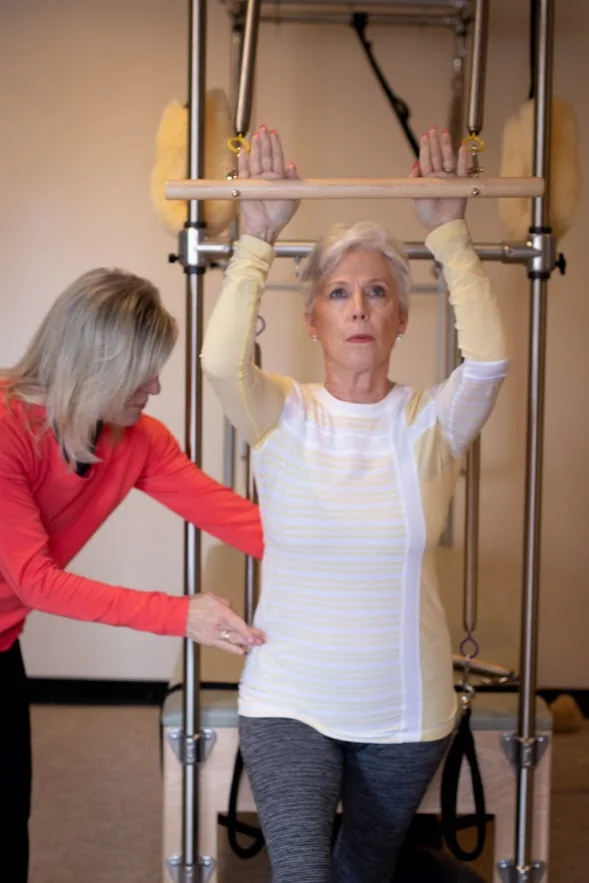 An instructor guides a client through a standing Pilates exercise in Overland Park